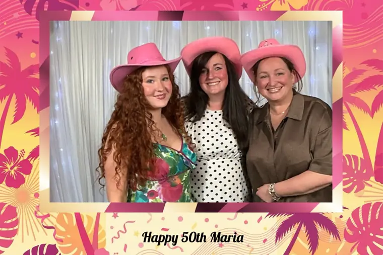 Tropical pink and yellow palm-print birthday photo booth print of three women in pink cowboy hats, captioned Happy 50th Maria