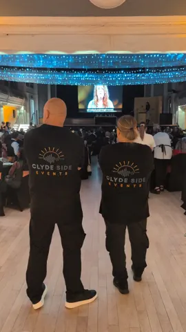 Clyde Side Events team in branded shirts watching the awards screen at the ICON Business Awards Inverclyde ballroom